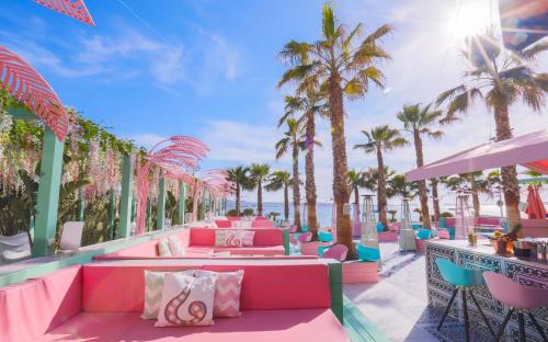 a resort patio with pink couches and palm trees at Wi-Ki-Woo Boutique Hotel in San Antonio