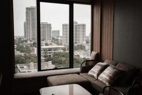 a living room with a couch and a large window at Homm Sukhumvit34 Bangkok - a brand of Banyan Group in Bangkok