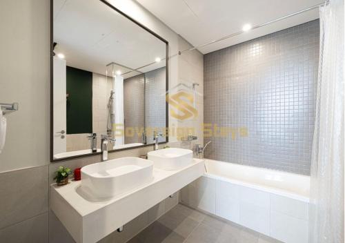 uma casa de banho com 2 lavatórios, uma banheira e um espelho. em 1 Residences Boutique 2 Bed Suite - Parking & Panoramic Views em Dubai