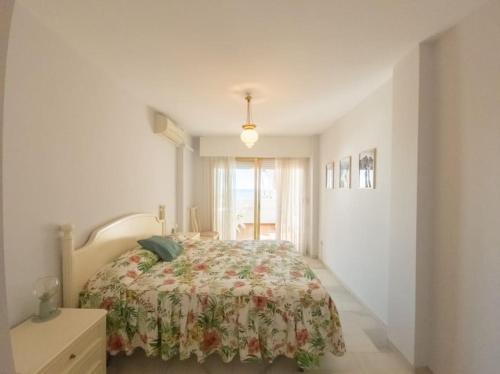 1 Schlafzimmer mit einem Bett mit Blumenbettdecke in der Unterkunft Gran apartamento primera línea in Estepona