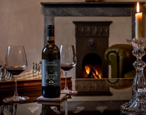 Villa Le Prata - Farm House & Winery - Adults Only في مونتالشينو: زجاجة من النبيذ موضوعة على طاولة مع كأسين