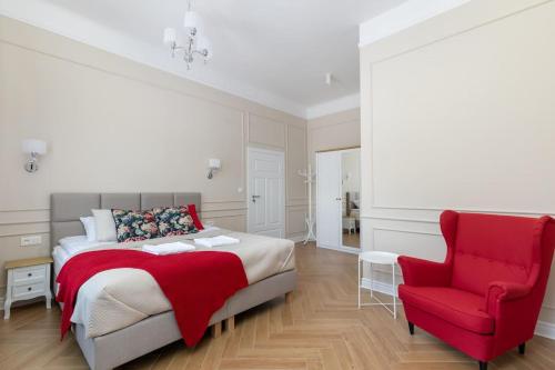 a bedroom with a bed and a red chair at Lwowska 9 - Intimate & Comfortable Studio by Noclegi Renters in Warsaw