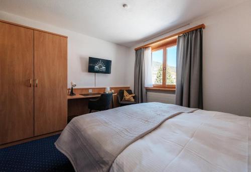 a hotel room with a bed and a desk and a window at Hotel Bünda Davos in Davos