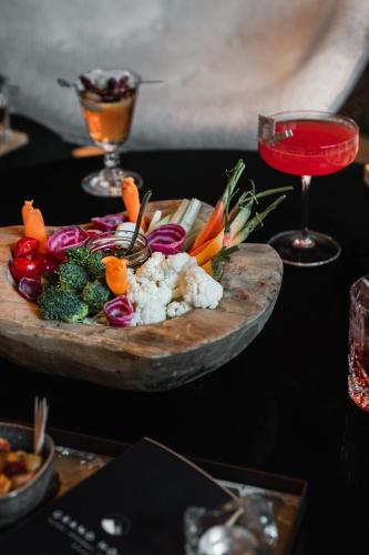 a plate of vegetables on a table with a drink at Grand Hôtel & Spa NUXE Serre Chevalier in Saint-Chaffrey