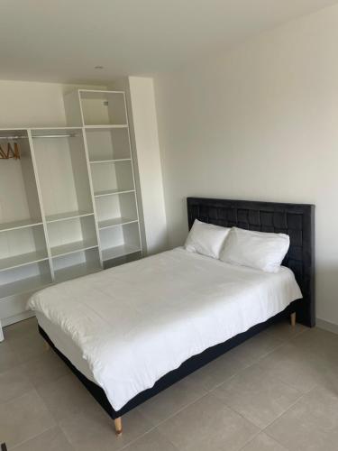 een slaapkamer met een bed met witte lakens en planken bij studio balcon, centre ville, parc expo, Arena in Pérols