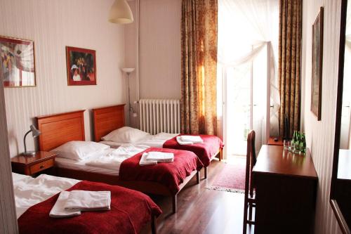 una camera d'albergo con tre letti con lenzuola rosse di Pensjonat Irena a Sopot