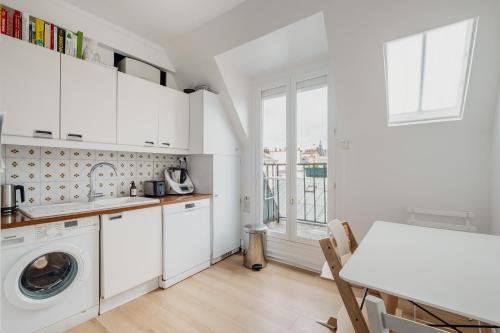 - une cuisine blanche avec un lave-linge et une table dans l'établissement Veeve - Bright Skies, à Paris