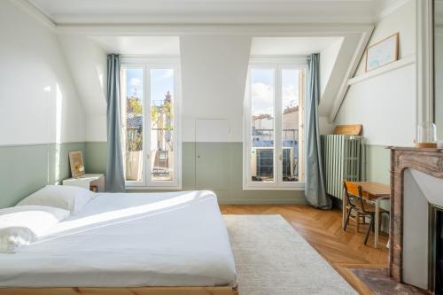 - une chambre avec un lit, une cheminée et des fenêtres dans l'établissement Veeve - Bright Skies, à Paris