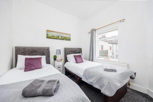 a bedroom with two beds and a window at Bright & Sunny 2BR Near Westcliff Beach & High St by Everhome Ltd in Southend-on-Sea