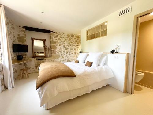 a bedroom with a white bed and a bathroom at Barbarens Maison d'hotes in Castelnau-Barbarens