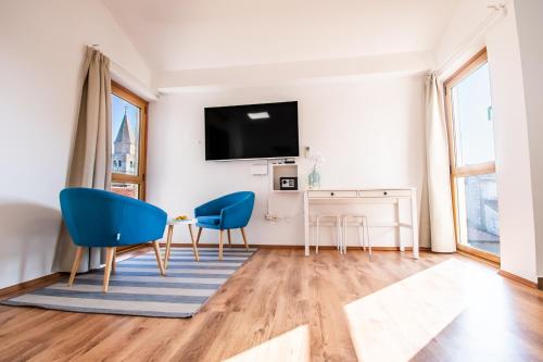a living room with two blue chairs and a table at apartment seafront Umag center old town seaview rentistra 4 in Umag