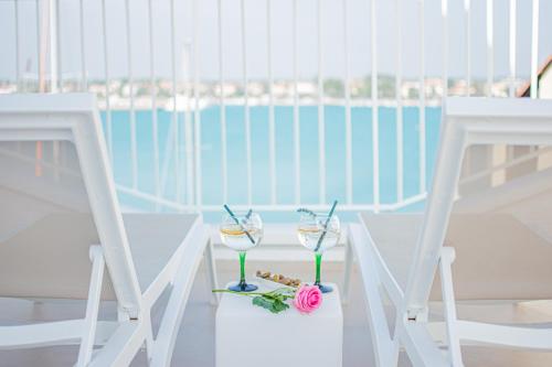 two glasses of wine sitting on a table with two chairs at Apartment seafront Umag center old town seaview 4 in Umag