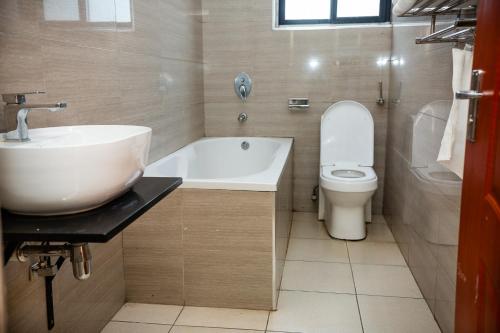 Eleganciana Lodges Limited في لوساكا: حمام مع حوض ومرحاض