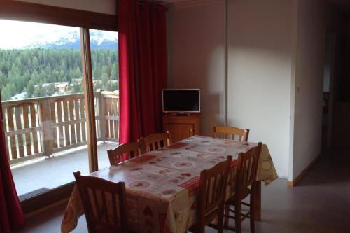 uma sala de jantar com uma mesa e uma grande janela em Superb well-equipped apartment em Le Dévoluy
