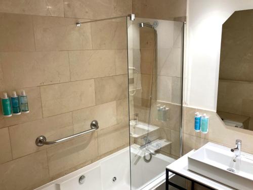 a shower with a glass door next to a sink at Hotel Miramar Valencia in Valencia