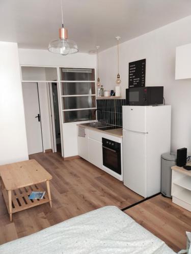 une cuisine avec un réfrigérateur blanc et une table dans l'établissement Le Lavoir - Studio centre ancien sur placette, à Toulon