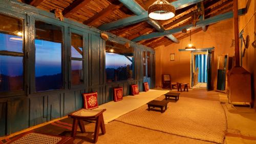 a room with tables and chairs and large windows at Kot Kailash Kumaon in Almora