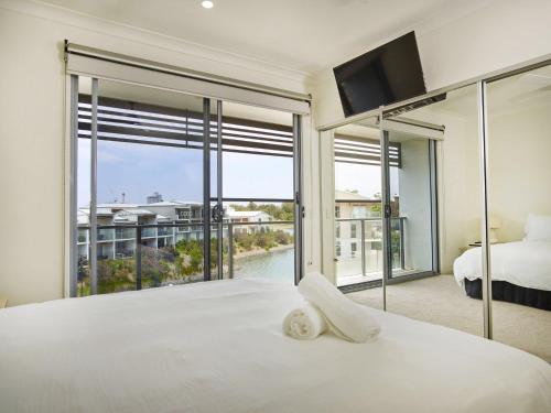 1 dormitorio con cama blanca y ventana grande en Emerald lakes 3 level villa en Gold Coast