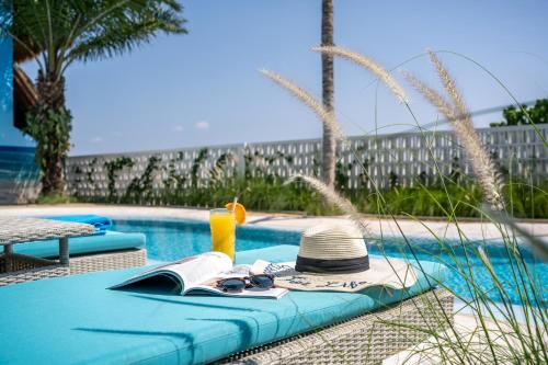 a table with a hat and a book next to a swimming pool at IZE Canggu by LifestyleRetreats in Canggu