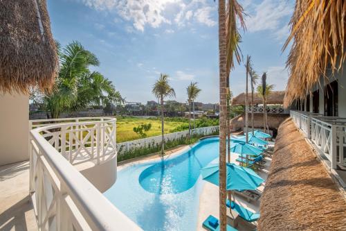 a resort pool with palm trees and chairs at IZE Canggu by LifestyleRetreats in Canggu