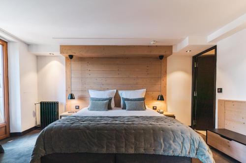 a bedroom with a large bed with a wooden headboard at Grand Hôtel & Spa NUXE Serre Chevalier in Saint-Chaffrey