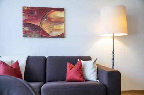 a blue couch with red and white pillows next to a lamp at Chasa Tulai F83 in Scuol