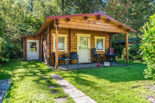 a wooden cabin with a table and chairs in a yard at Camping het Bosbad in Emmeloord