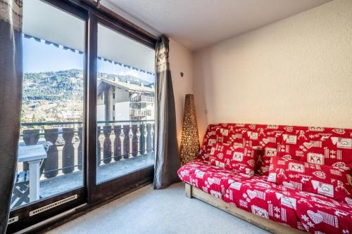 a living room with a red couch and a large window at Studio Chatel - Au pieds du Linga in Châtel