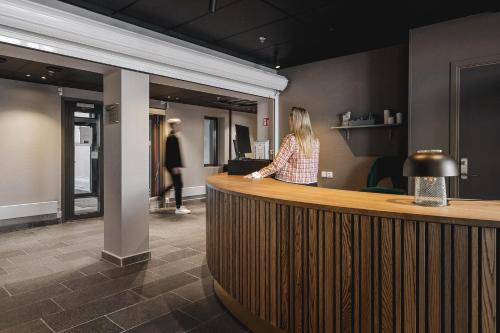 a woman standing at a counter in a lobby at Enter St. Elisabeth Suites in Tromsø
