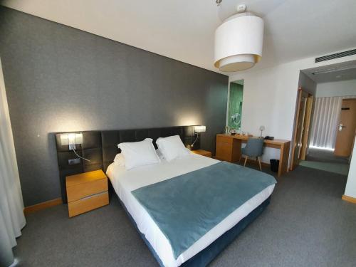 a bedroom with a large bed and a desk at Hotel Pedras Salgadas in Pedras Salgadas