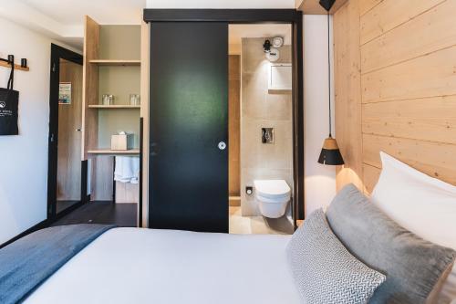 a bedroom with a large bed and a bathroom at Grand Hôtel & Spa NUXE Serre Chevalier in Saint-Chaffrey