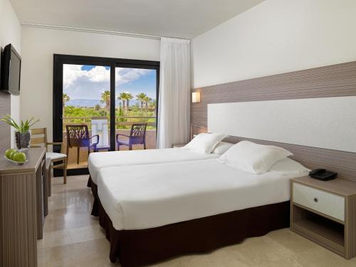 a hotel room with a bed and a balcony at H10 Cambrils Playa in Cambrils