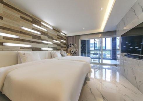a bedroom with two white beds and a large window at Ulsan Samsan Pandora Hotel in Ulsan