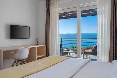a bedroom with a bed and a desk and a balcony at Villa Antares in Duće