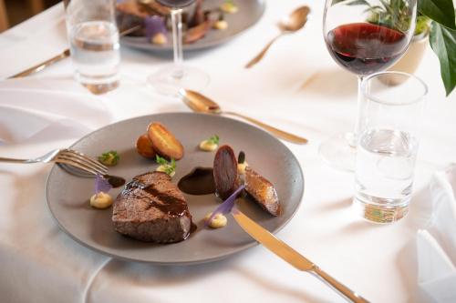 a plate of food on a table with wine glasses at Hotel Restaurant Capricorns in Wergenstein