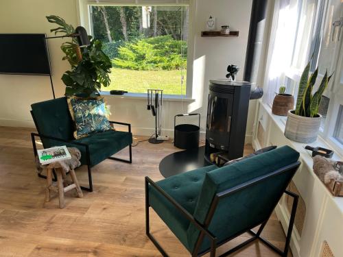 een woonkamer met een bank, een stoel en een fornuis bij "Zonnekind" Atmospheric holiday home in Noordwijkerhout near the beach in Noordwijkerhout