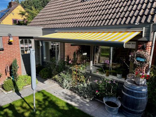 a house with a striped awning and some plants at "Zonnekind" Atmospheric holiday home in Noordwijkerhout near the beach in Noordwijkerhout