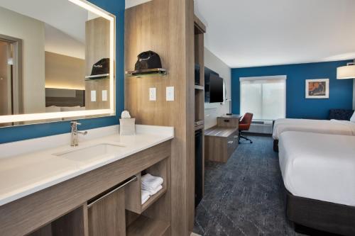 a bathroom with a sink and a bed in a room at Holiday Inn Express Kitty Hawk - Outer Banks, an IHG Hotel in Kitty Hawk