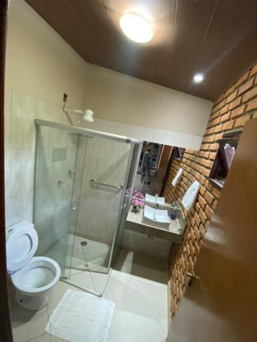 uma casa de banho com uma cabina de duche em vidro e um WC. em Casa GMafra em Rio de Contas
