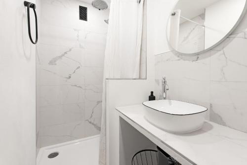 een witte badkamer met een wastafel en een spiegel bij T3 Hyper Centre - Chaleureux et lumineux in Toulouse