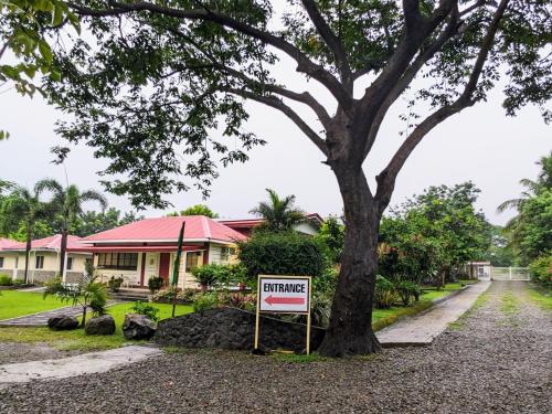a house with a sign in front of a tree at VistaBerge - Private, Nature, History in Bagac
