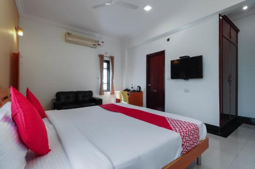 a bedroom with a large white bed with red pillows at Emara Grand Hotel in Bangalore