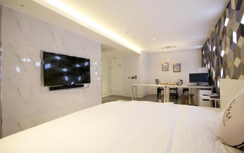 a bedroom with a bed with a television on a wall at Ulsan Samsan Pandora Hotel in Ulsan