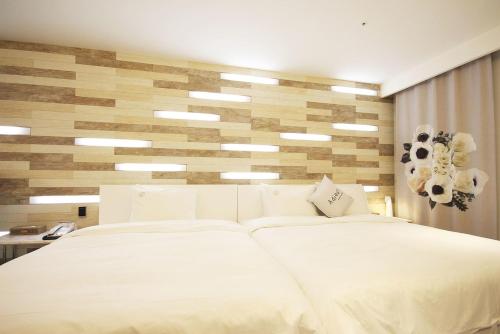 a bedroom with two white beds and a wooden wall at Ulsan Samsan Pandora Hotel in Ulsan