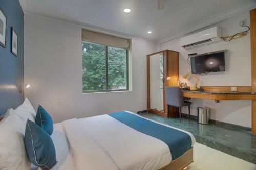 a bedroom with a bed and a desk and a television at OYO SilverKey Hotel Manas Residency in Mumbai