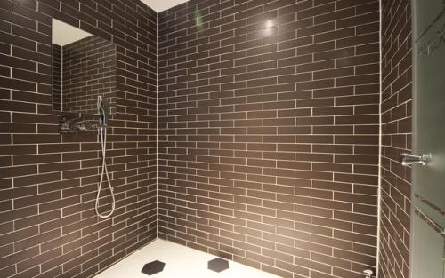 a bathroom with a shower with brown tiled walls at Ulsan Samsan Pandora Hotel in Ulsan