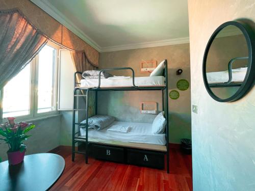 a room with two bunk beds and a mirror at Ostello Bello Roma Colosseo in Rome