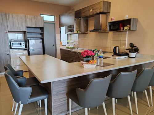 a kitchen with a large wooden island with chairs at Kensington Sunrise at Sg Palas,PalasHorizon in Tanah Rata