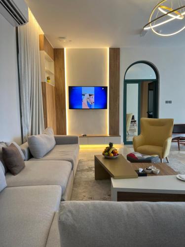 a living room with a couch and a tv on the wall at Dibba Mountain Park Resort in Fujairah