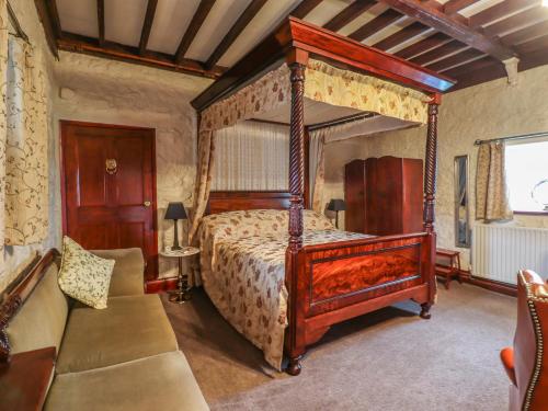 Longwitton的住宿－The Barn，一间卧室配有天蓬床和沙发